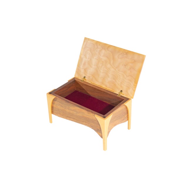 A wooden jewelry box designed by the American artist Mark Rehmar. The two-tone wooden jewelry box has four legs and a...