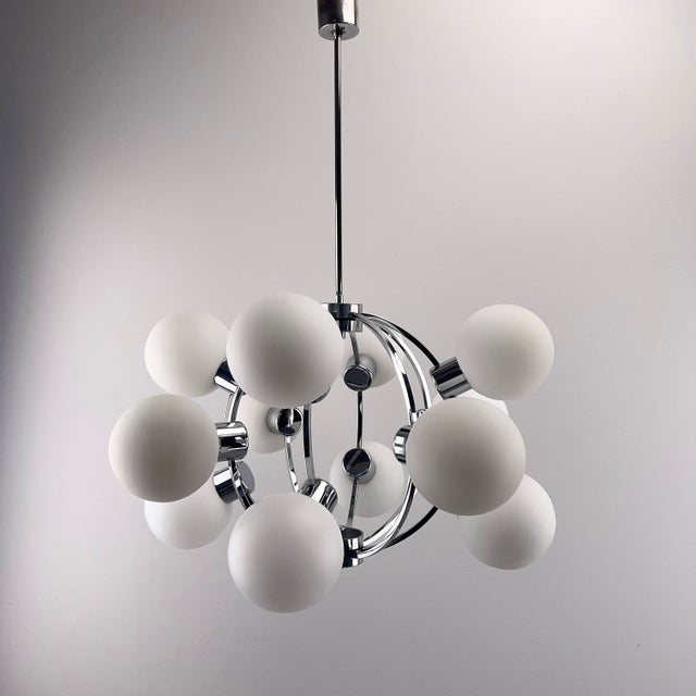 Stunning chandelier made of chrome-plated metal with 12 white glass globes in beautiful condition. Very chic space-age...