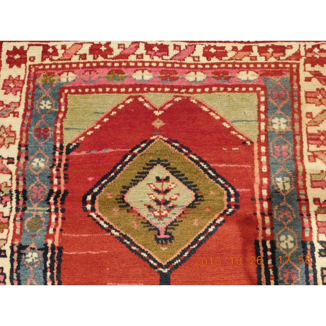 Rich in tone with nomadic influence. Red background displaying five diamond medallions in geometric styles. Multi borders....