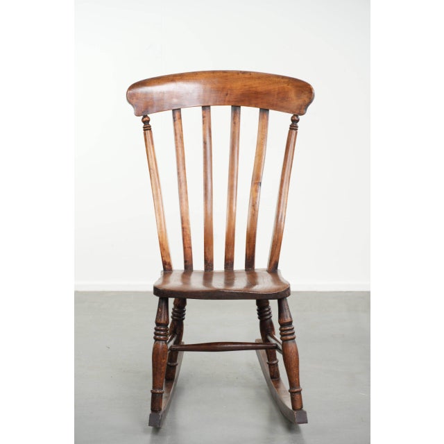 We are offering this antique English oak Windsor rocking chair from the early 19th century, featuring beautiful warm...