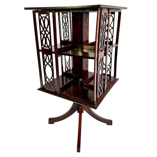 A Mahogany Revolving Bookcase, the figured mahogany top with satinwood banding, with Chippendale-style fretwork side...