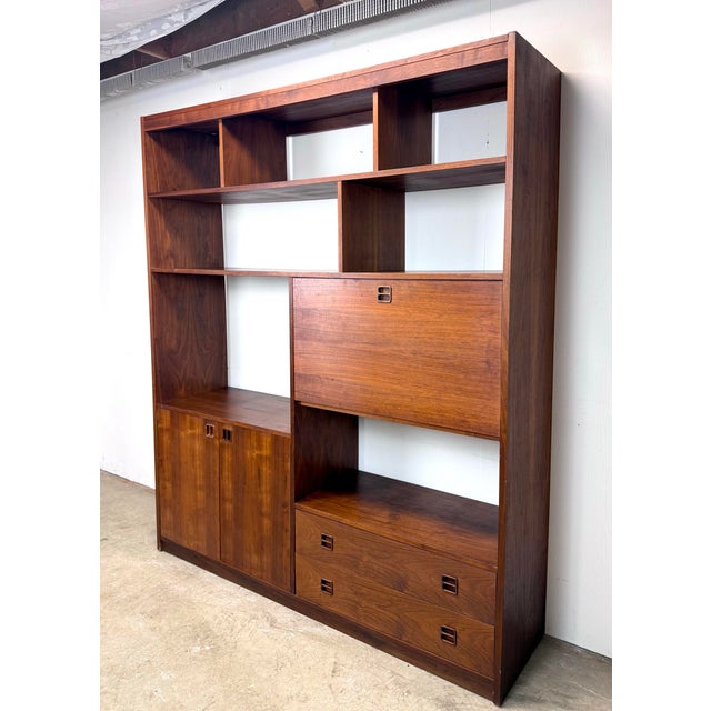 A beautiful mid century modern walnut wall unit featuring plenty of shelf space for books, vinyl records and objects, a...