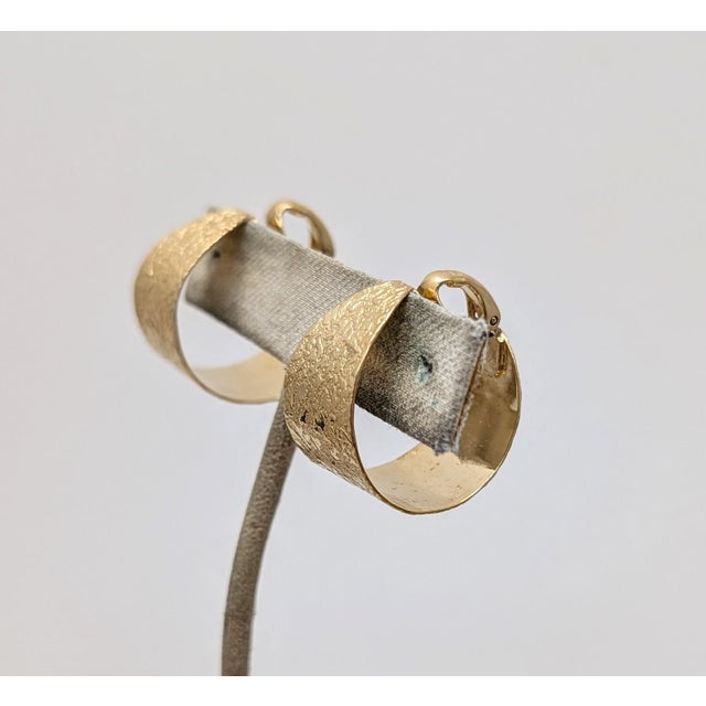 1970s goldtone smooth and textured hoop clip earrings. Marked crown "TRIFARI ©." Measure: 1 inch tall by 5/8 inches wide...