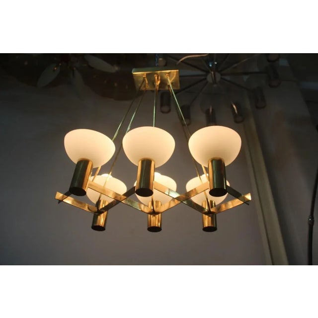 This chandelier was manufactured by Stilnovo around the 1950s. It is made from brass with opaline glass cup shaped shades....