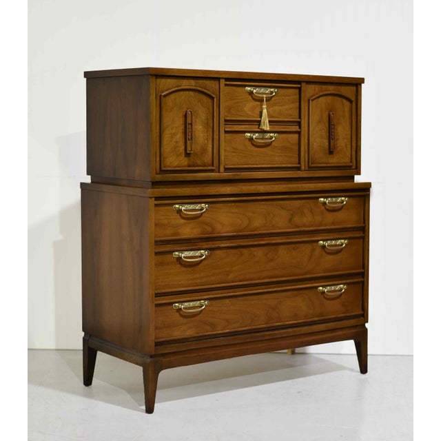 Clean lines, warm wood tones, shiny brass hardware and timeless design define this 1960s mid-century modern walnut highboy...