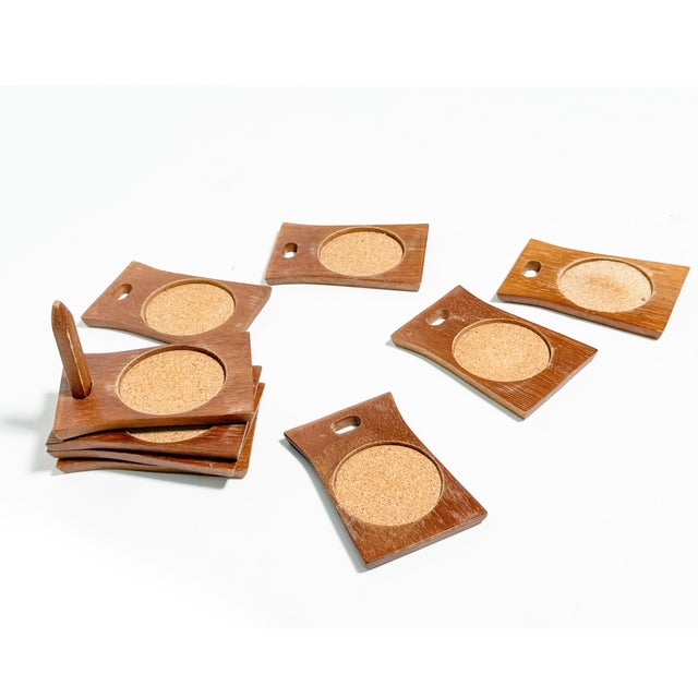 A fabulous vintage mid-century modern coaster set featuring eight rectangular wooden coasters with recessed circular cork...