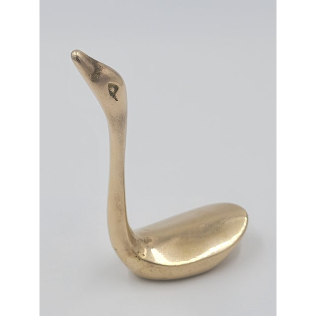 This elegant solid brass swan figurine features a sleek, minimalist design characteristic of mid-century modern decorative...