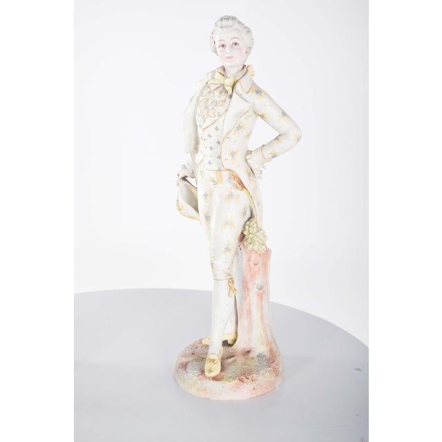 Pair of European porcelain statuettes, representing a lady and a gentleman, positioned in graceful poses, on a textured...