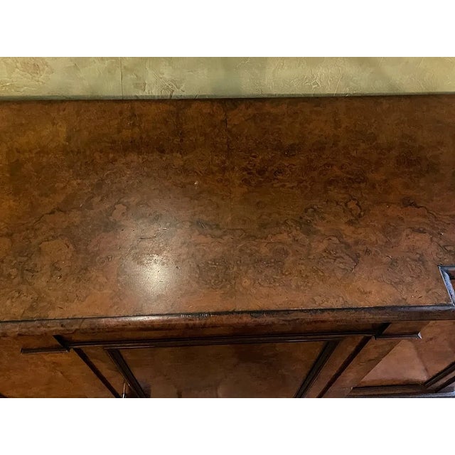 Elegant burl walnut sideboard cabinet featuring a richly figured high-gloss wood grain, three paneled cabinet doors,...