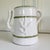 Stunning white glazed pottery pitcher featuring an elegant botanical relief design, accented with hand-painted green trim....