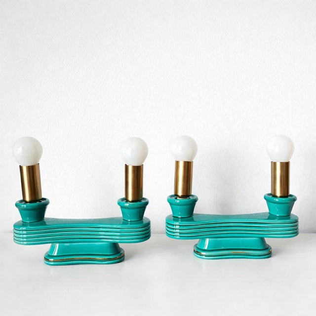Pair of Art Deco ceramic candlesticks, converted into lamps. Emerald green glazed ceramic candlesticks with a gold rim....