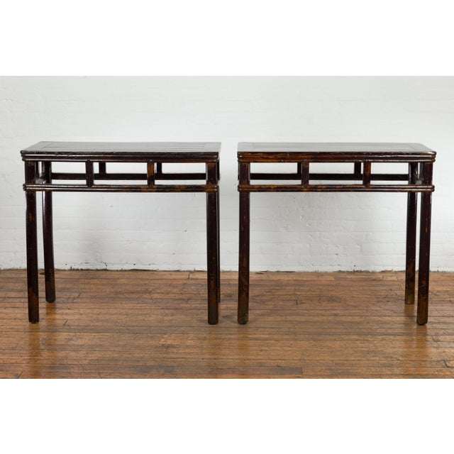 A pair of Chinese late Qing Dynasty period wine console tables from circa 1900 with black/brown lacquer, open apron,...