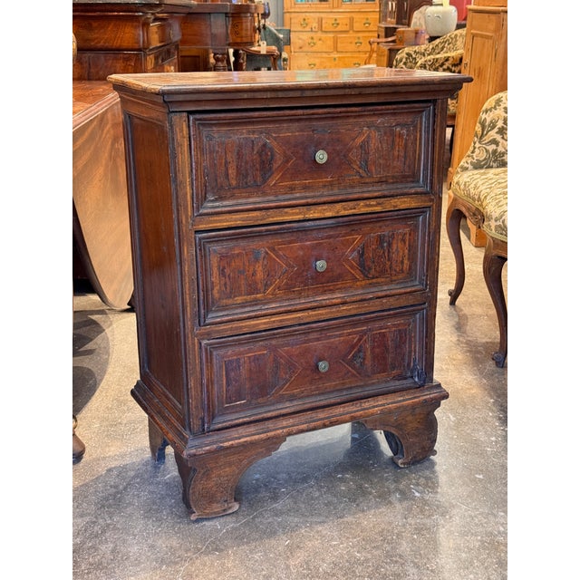 A small and characterful 18th century Italian commode with three drawers, each front decorated with geometric inlay in a...