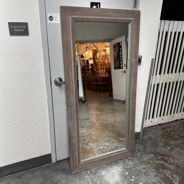 Design Plus Gallery presents a Rustic Wood Framed Floor Mirror. This oversized rectangular mirror showcases a wide wood...