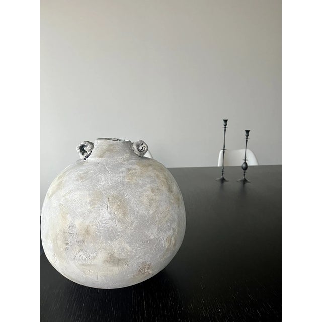 A handcrafted ceramic vessel with curved profile and round handle-like accents, sculptural, organic, and perfect for...
