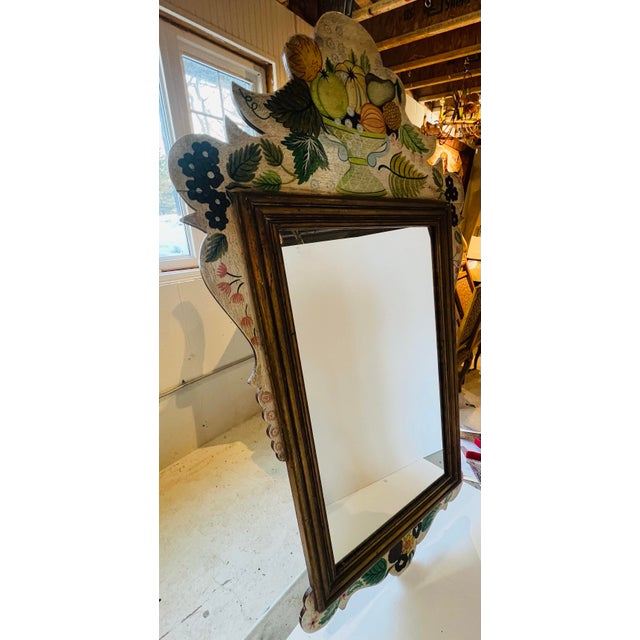 Charming vintage wall mirror featuring an ornate hand-painted fruit and foliage surround with a classic gilt wood frame...