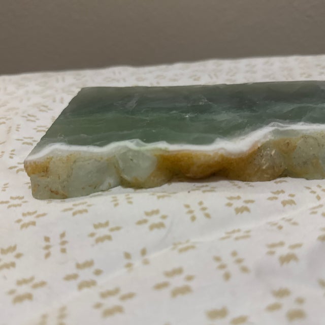 A striking natural fluorite slab showcasing layered bands of soft violet, green, and translucent crystal structure....