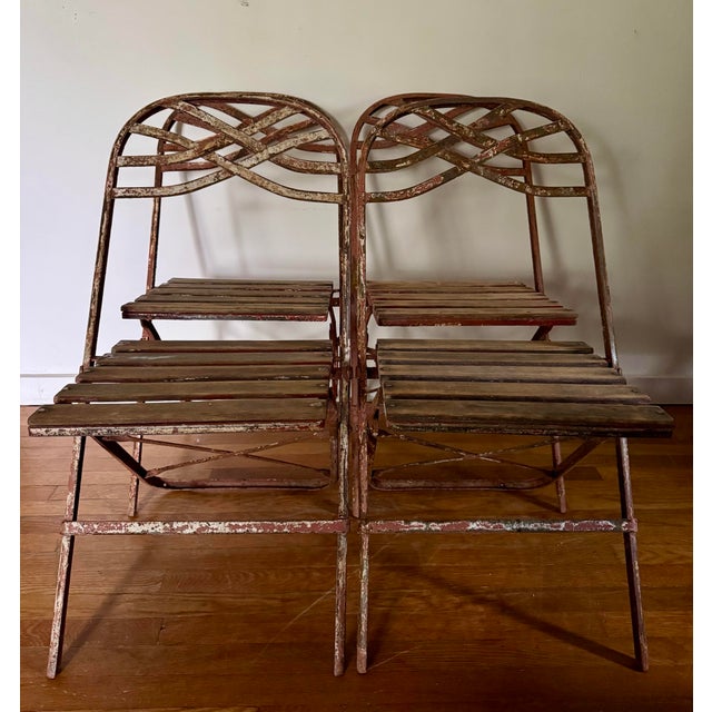 Antique French wrought iron folding garden chairs from the 19th century, featuring a twisted backrest design and wooden...