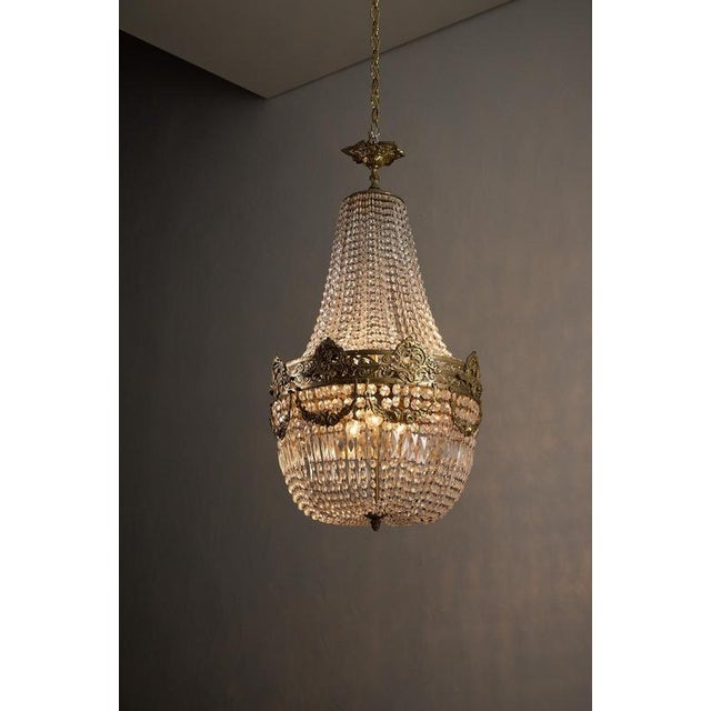 Empire-style crystal chandelier dates from the mid-20th century and evokes the grandeur of French Neoclassical design....