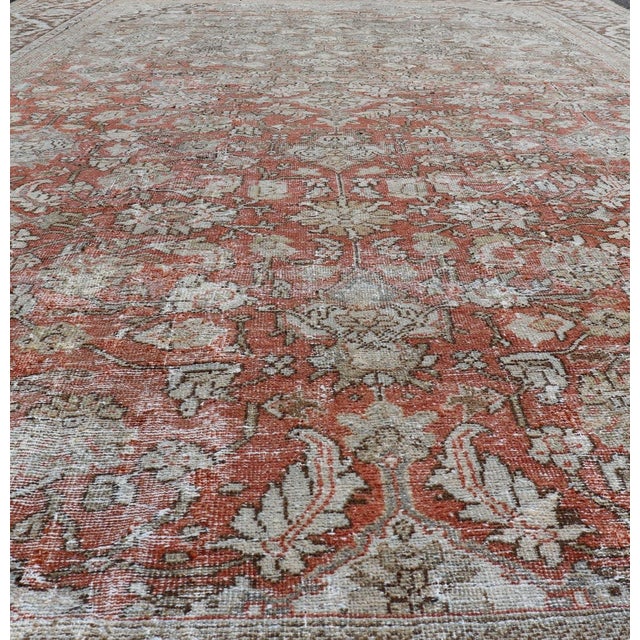 This antique Persian Sultanabad rug an all-over sub-geometric floral design rendered in orange and earthy tones, set upon...
