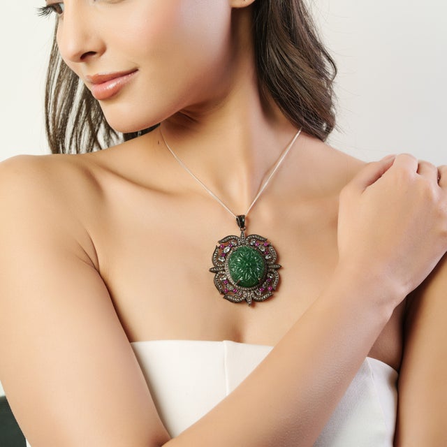 Crafted in 925 sterling silver, this elegant pendant features a hand-carved natural Green Aventurine centerpiece measuring...