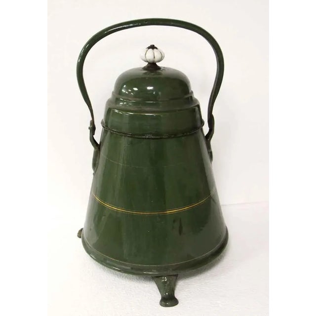 Green enameled pot with gold painted details and a handle. The top opens and comes off with a white ceramic button at the...