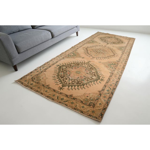 This is a vintage Turkish Oushak rug from the Mid 20th Century. The piece was hand-knotted.