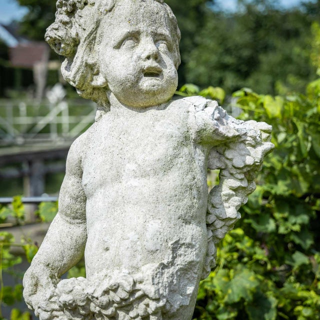 Cast stone garden figure in the shape of a putto as the personification of spring, dressed with a garland of flowers and...