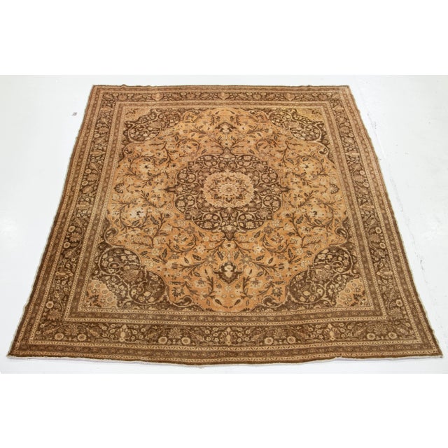 This vintage hand-knotted Tabriz wool rug has a tan field with brown and beige accents allover the medallion motif. This...