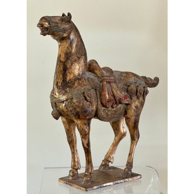 A wooden Tang Dynasty style wooden horse with gilded and polychrome finish. Finely carved in detail and expression. From...