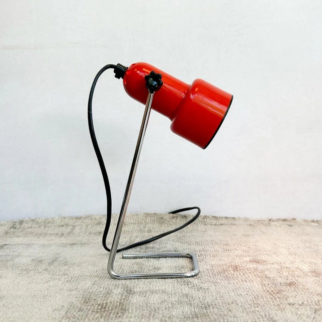 A vintage mid century red spotlight desk lamp by habitat. the lamp features a red plastic shade, raised on chromed wire...
