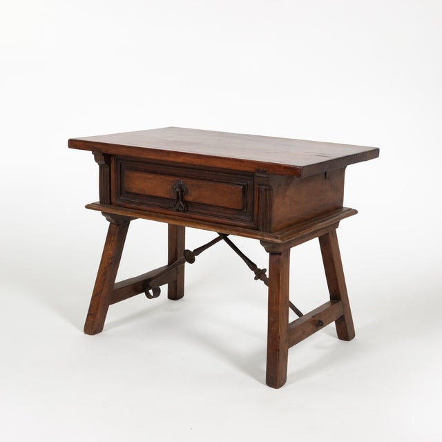 A Spanish low table in chestnut with rectangular single-slab top and a molded single drawer front, framed by recessed...