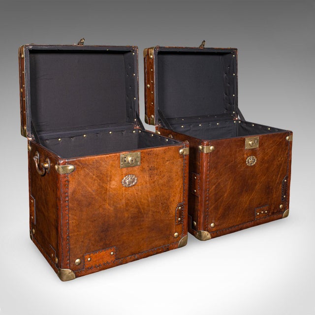 This is a pair of late vintage campaign luggage trunks. An English, leather and brass bedside nightstand, or occasional...