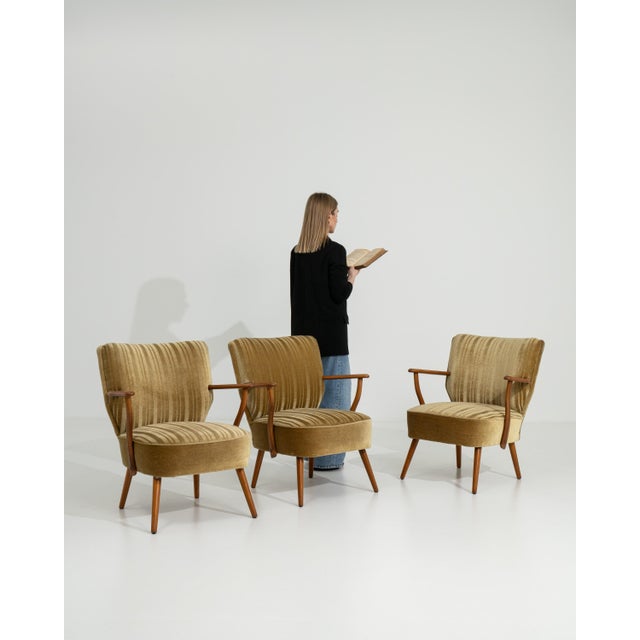 A set of three mid-century modern armchairs from Denmark, featuring wooden frames with upholstered seats and backs. The...