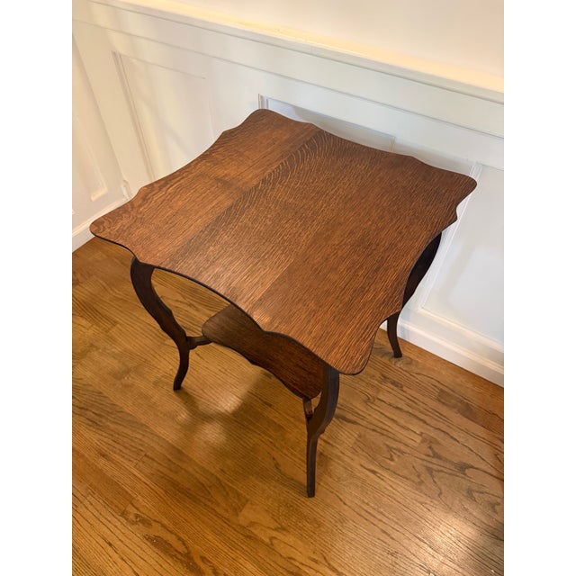 A distinctive antique oak occasional table featuring a beautifully shaped square top with expressive wood grain, a...