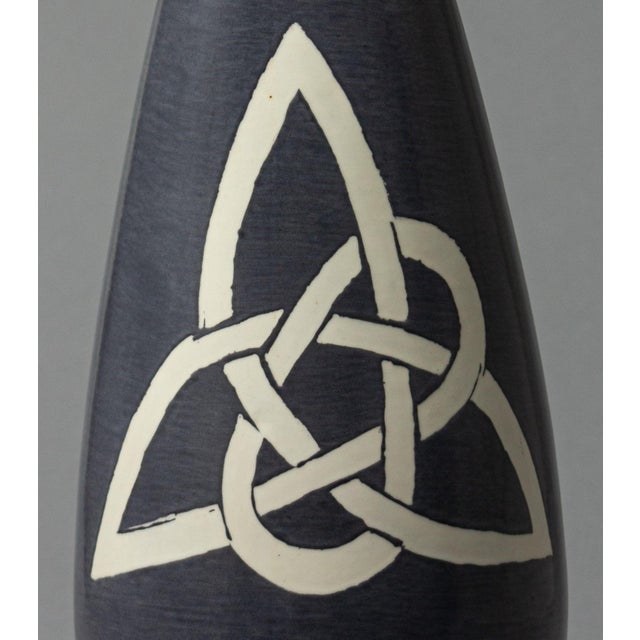 A large ceramic vase in an elegant cone shape in clay, made by Irish artist Gabrielle, featuring a Trinity Knot...