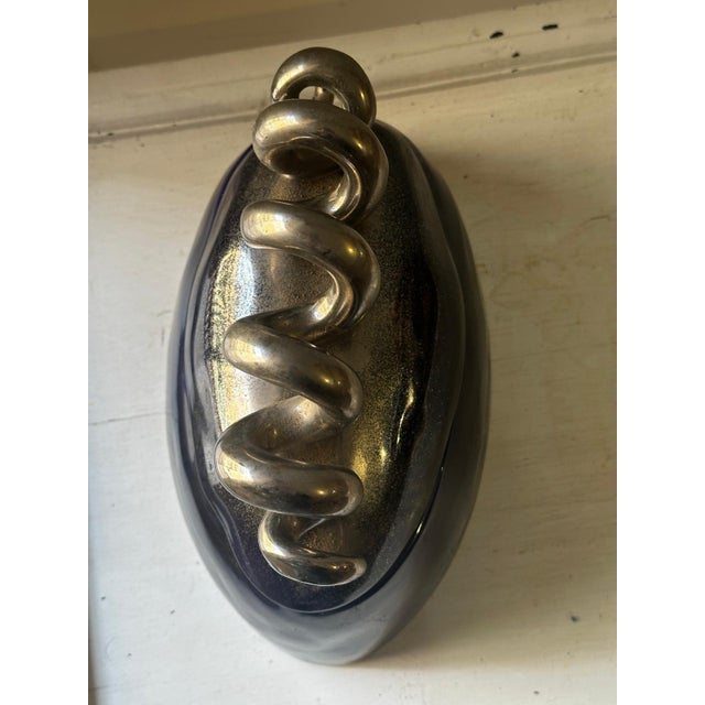 Oval decorative box in deep blue glazed ceramic, topped with a spectacular spiral design in a silver metallic finish. The...