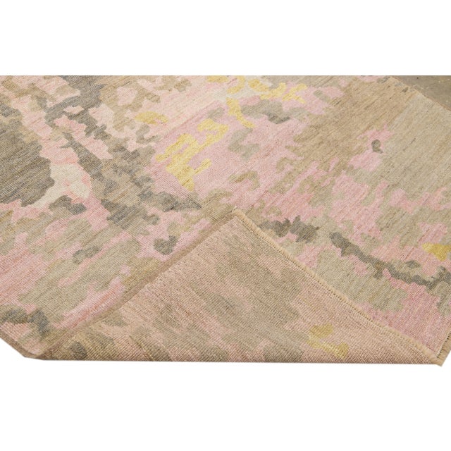 Beautiful handmade wool rug with a pink field. This Modern rug has a brown, yellow, and gray accent featuring a gorgeous...