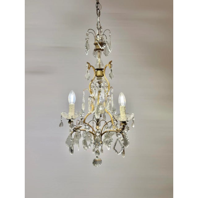 Italian Louis XV Style Gilt Brass and Bohemian Crystal 3-Light Chandelier, 1950s This charming piece features a finely...