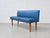 A characterful vintage bench with a blue faux leather cover, a straight backrest, and slender wooden legs. The minimalist...