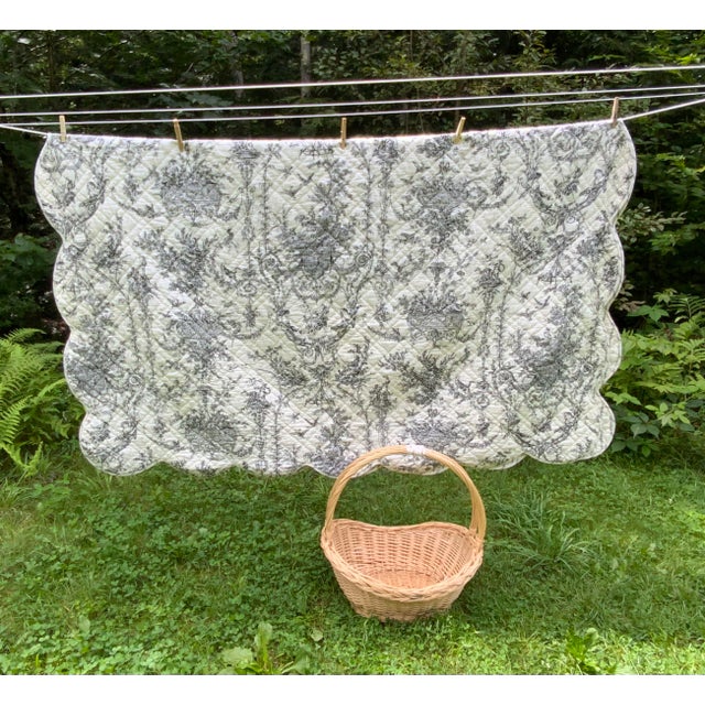 A vintage quilt in the French country tradition, printed with a classic black and white toile de Jouy pattern — pastoral...