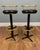 A stylish pair of mid-century modern bar stools featuring a striking combination of black leather seats and brass-finished...