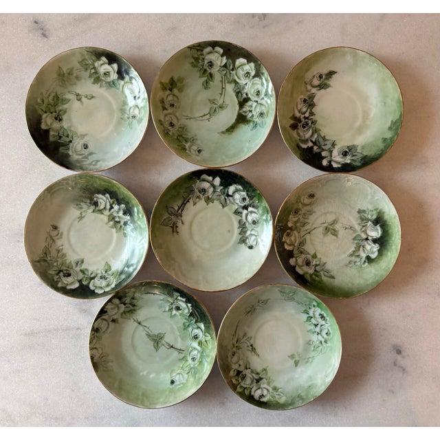 Set of 8 small porcelain plates or saucers with hand painted green and white rose Victorian design and gold edges. Likely...