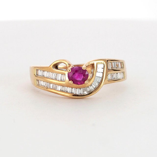 A sophisticated ring featuring a 0.29 carat round-cut ruby of a vivid red color. The ring is accented by 0.31 carats of...