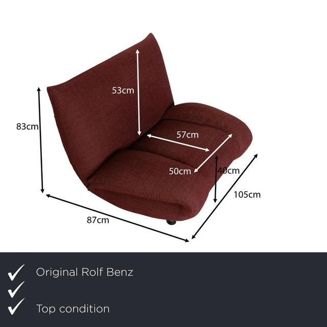 The Rolf Benz armchair is upholstered in a wine-red fabric and stands on round metal legs. It features a curved design and...