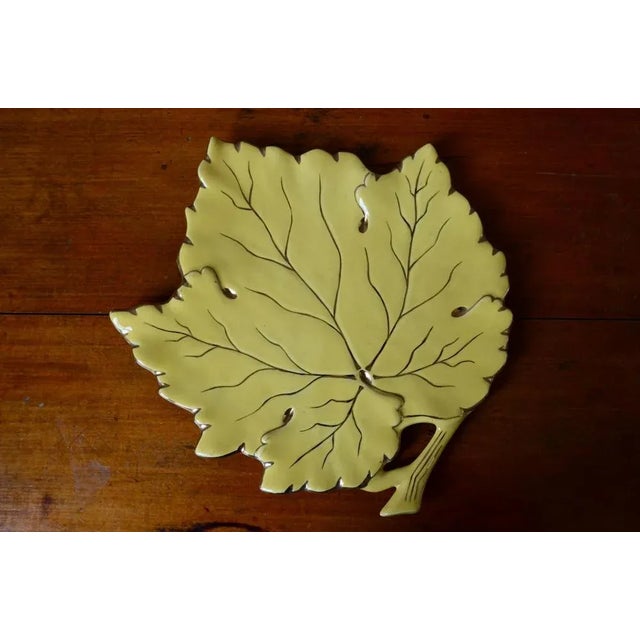 Unlikely ceramic and unclassifiable, this piece is very typical Midcentury. Large leaf, ribs and edges enhanced with gold,...