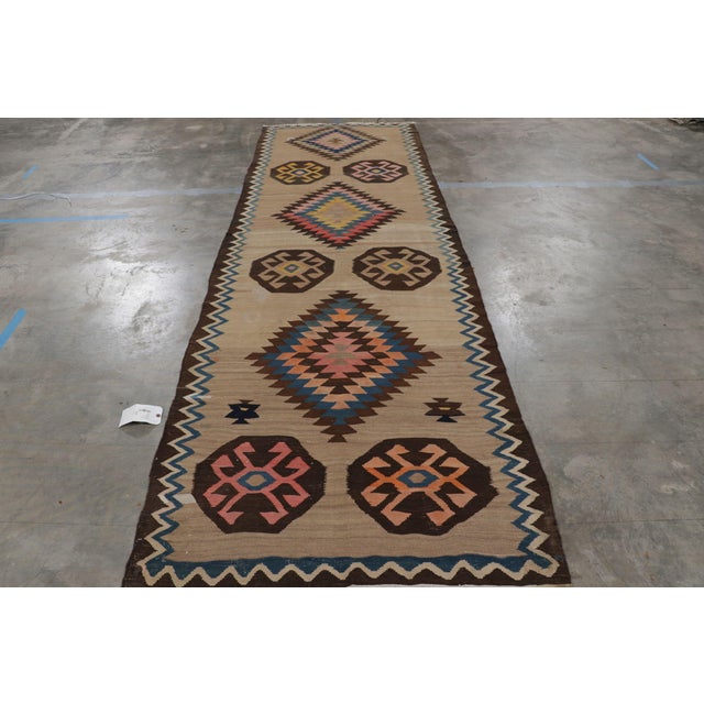 Handwoven in wool circa 1920, this 4x13 antique Persian Kilim and gallery runner is an exciting new curation from Rug &...
