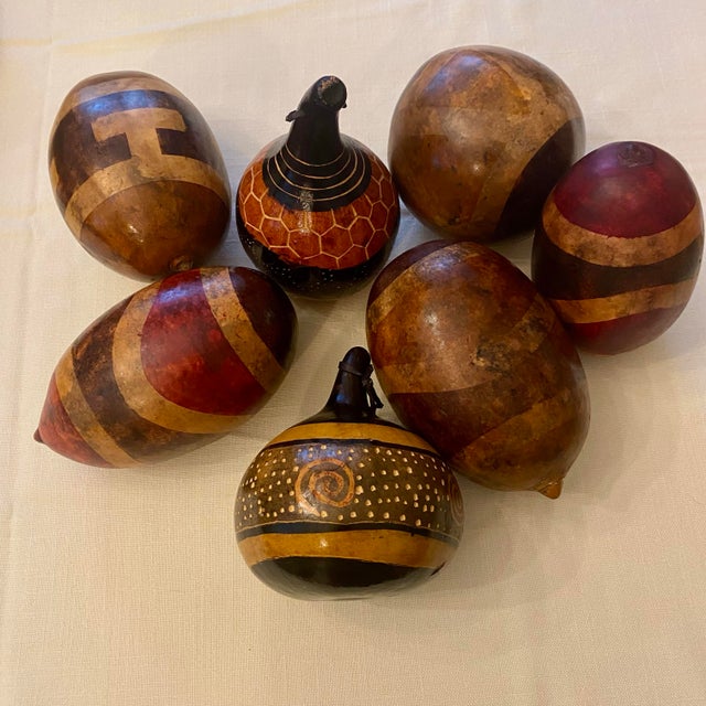 A striking set of seven vintage hand painted gourds, each finished in warm earth tones and bold geometric motifs. The...