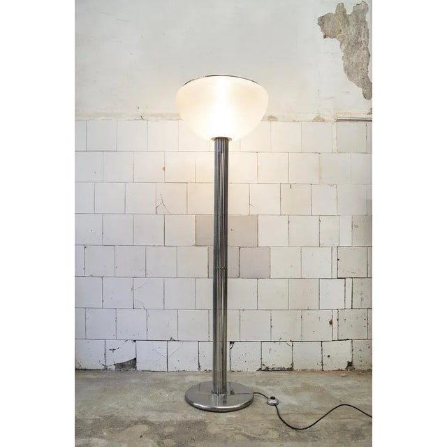 Floor lamp with base and tubular structure in chromed steel and opaque white plastic lampshade. Moana model Designer Luigi...