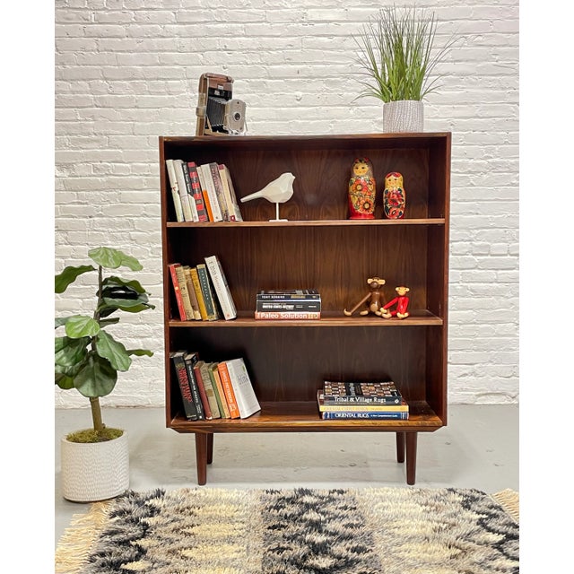 Simple + Classic Mid Century Modern ROSEWOOD bookcase, c. 1960's. This stunning piece features three wide and long...